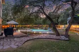 Evening view of the backyard pool with string lights and grill area