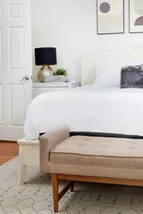 Bedroom detail with upholstered bench at the foot of a crisply made bed