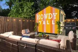Backyard lounge area with sectional seating, grill, and a colorful painted shed