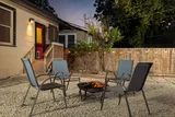 Backyard fire pit with four chairs and string lights at dusk