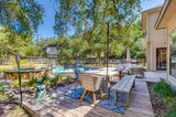 Sunny deck with outdoor dining table and bench beside the pool and spa
