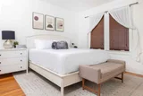 Primary bedroom with queen bed, wood blinds, and layered rug