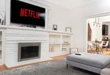 Living room with white brick fireplace, mounted TV, and view into the dining area
