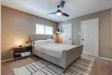 Guest bedroom with upholstered bed, ceiling fan, and soft lighting