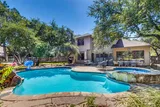 Daytime view of the pool and attached spa surrounded by shade trees